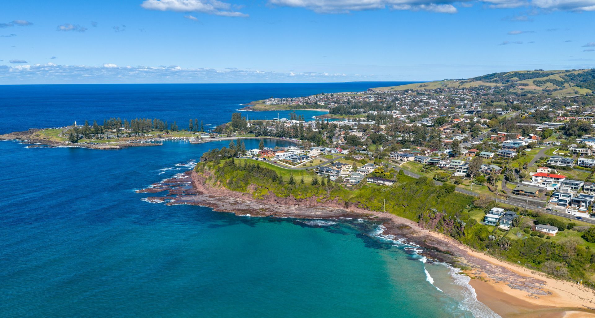 Modern white apartment building with blue accents, blue sky, and green grass.