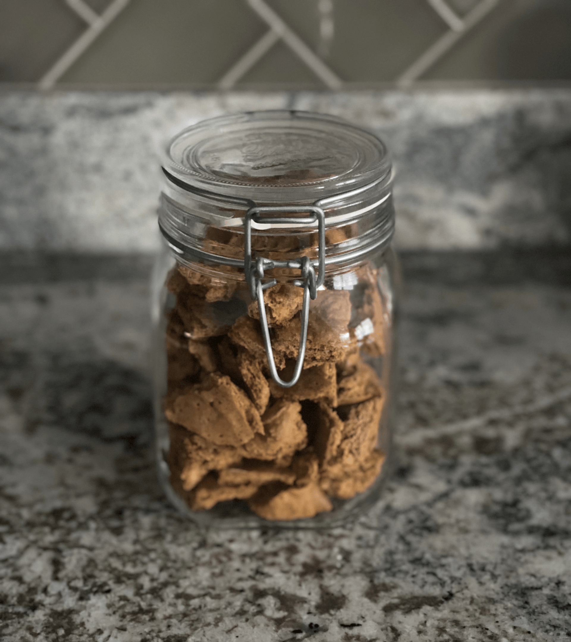 a glass jar filled with  dog cookies is sitting on a counter .