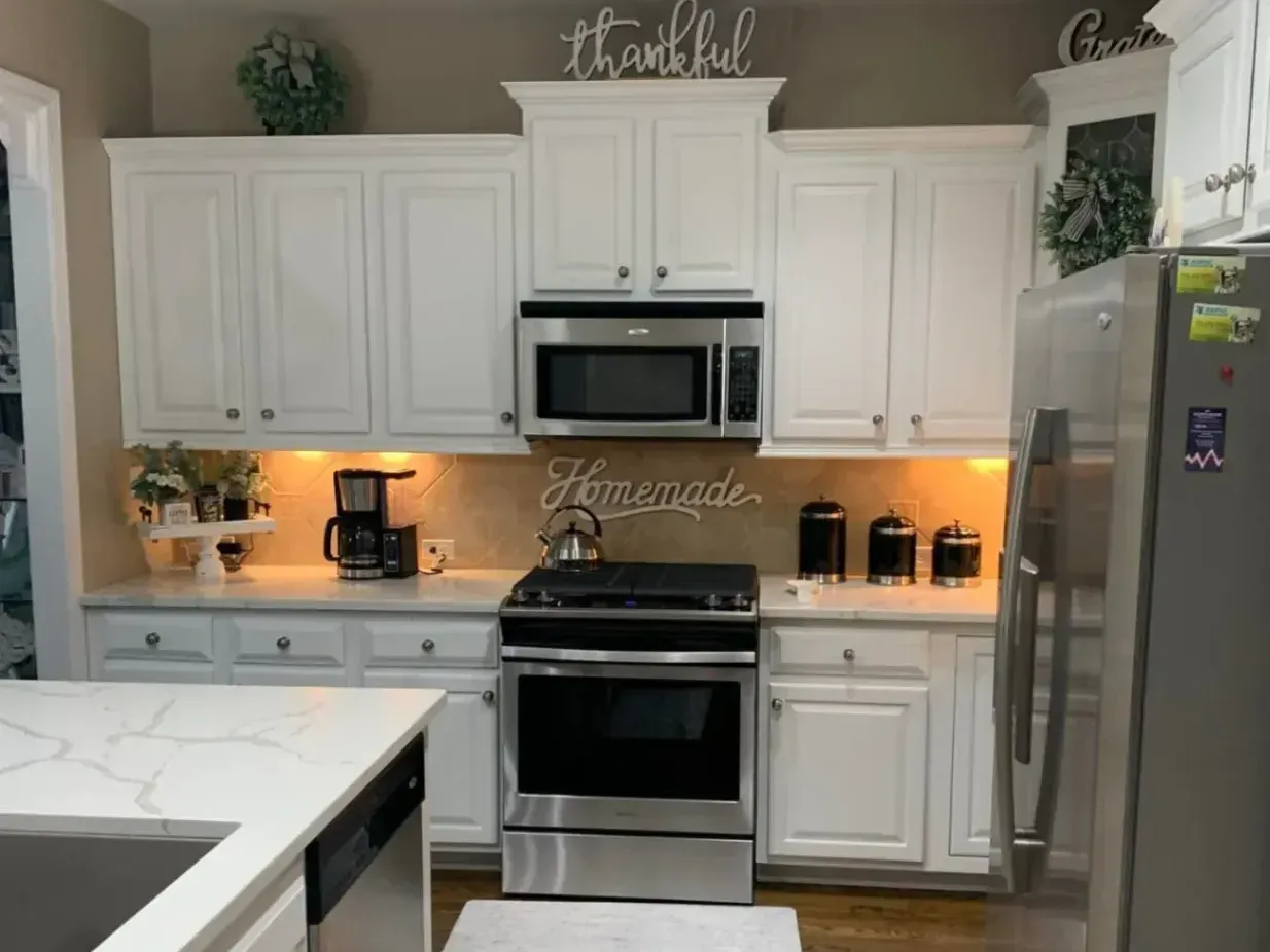 A man is painting the side of a house with a ladder.
