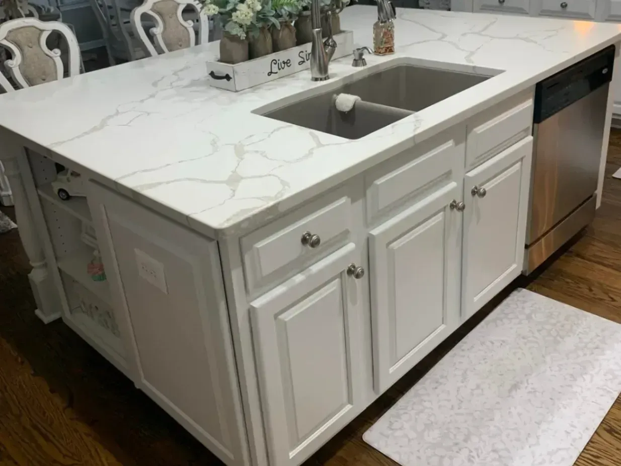 A kitchen with a large island with a sink and a dishwasher.