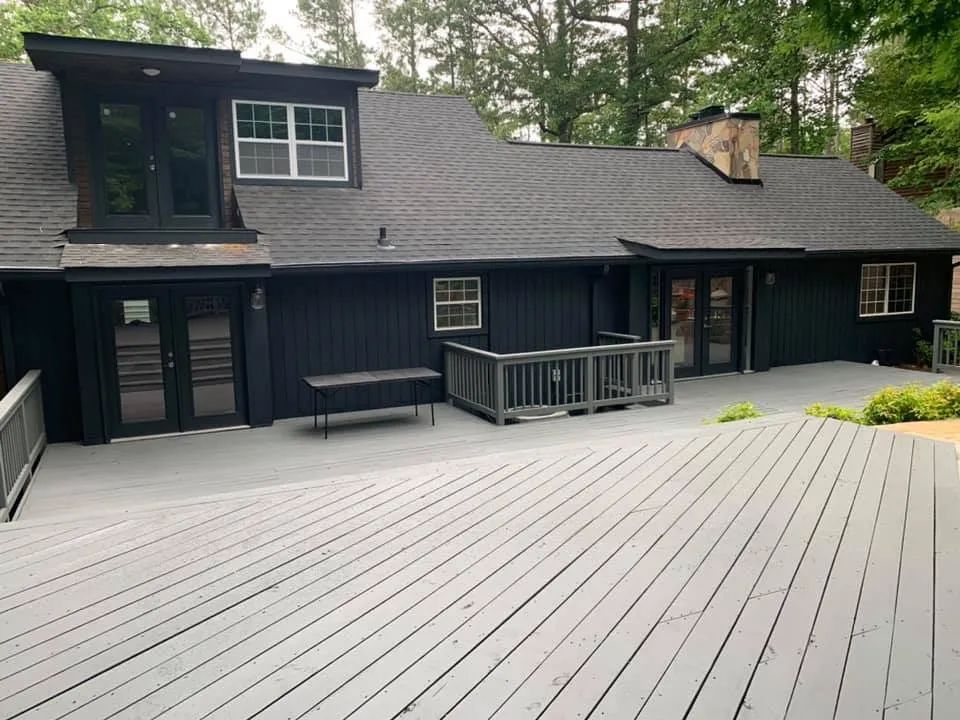 A black house with a gray deck in front of it