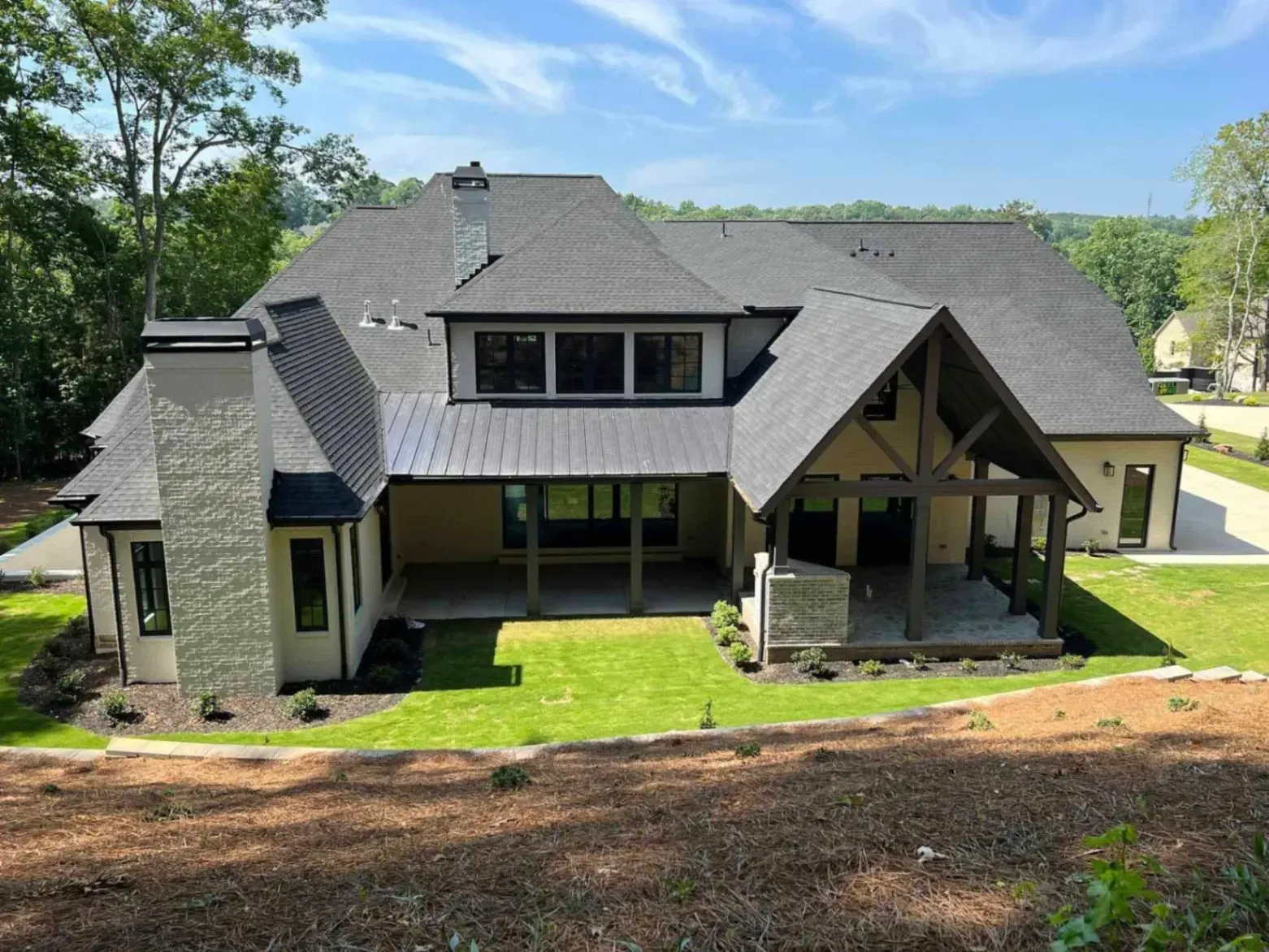 A large house with a gray roof is sitting on top of a lush green hillside.