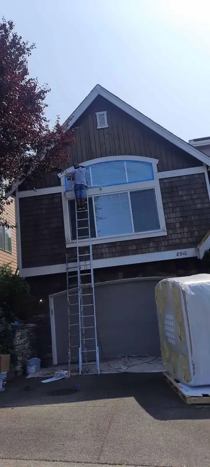A man is standing on a ladder painting a house.