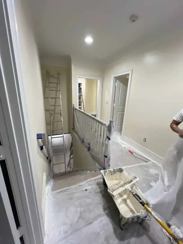 A man is painting a hallway with a roller.