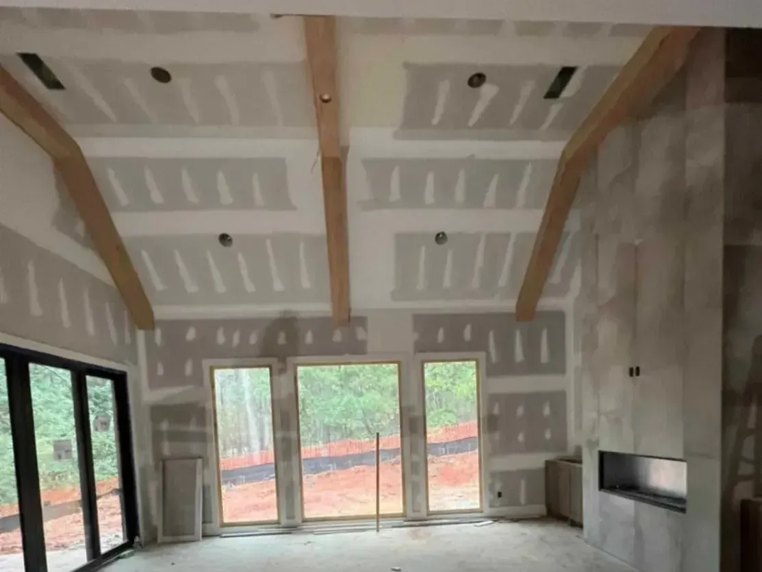 A large empty room with a lot of windows and drywall.
