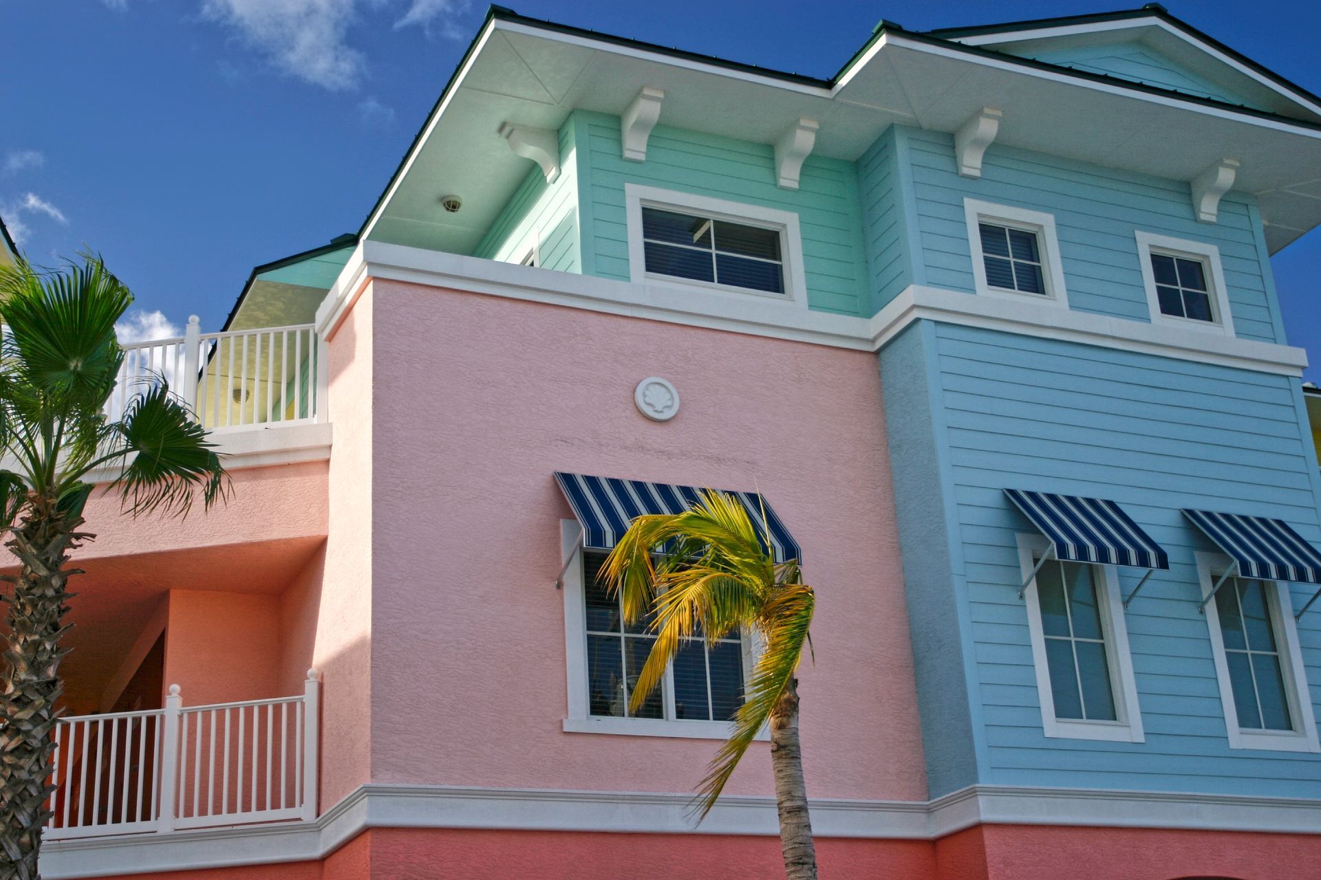 A large blue and white house with palm trees in front of it