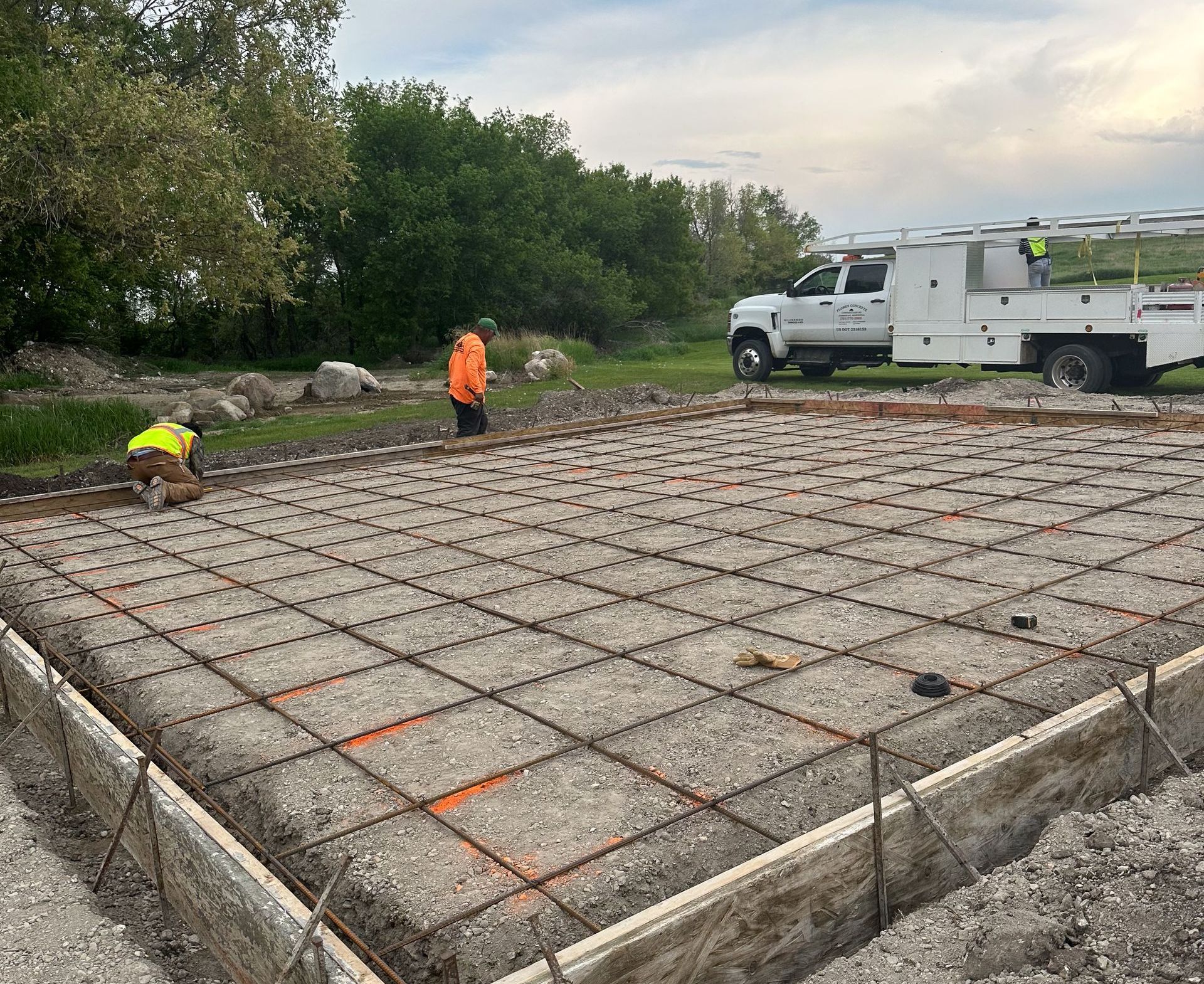 A concrete base for a house is being built on a dirt field.