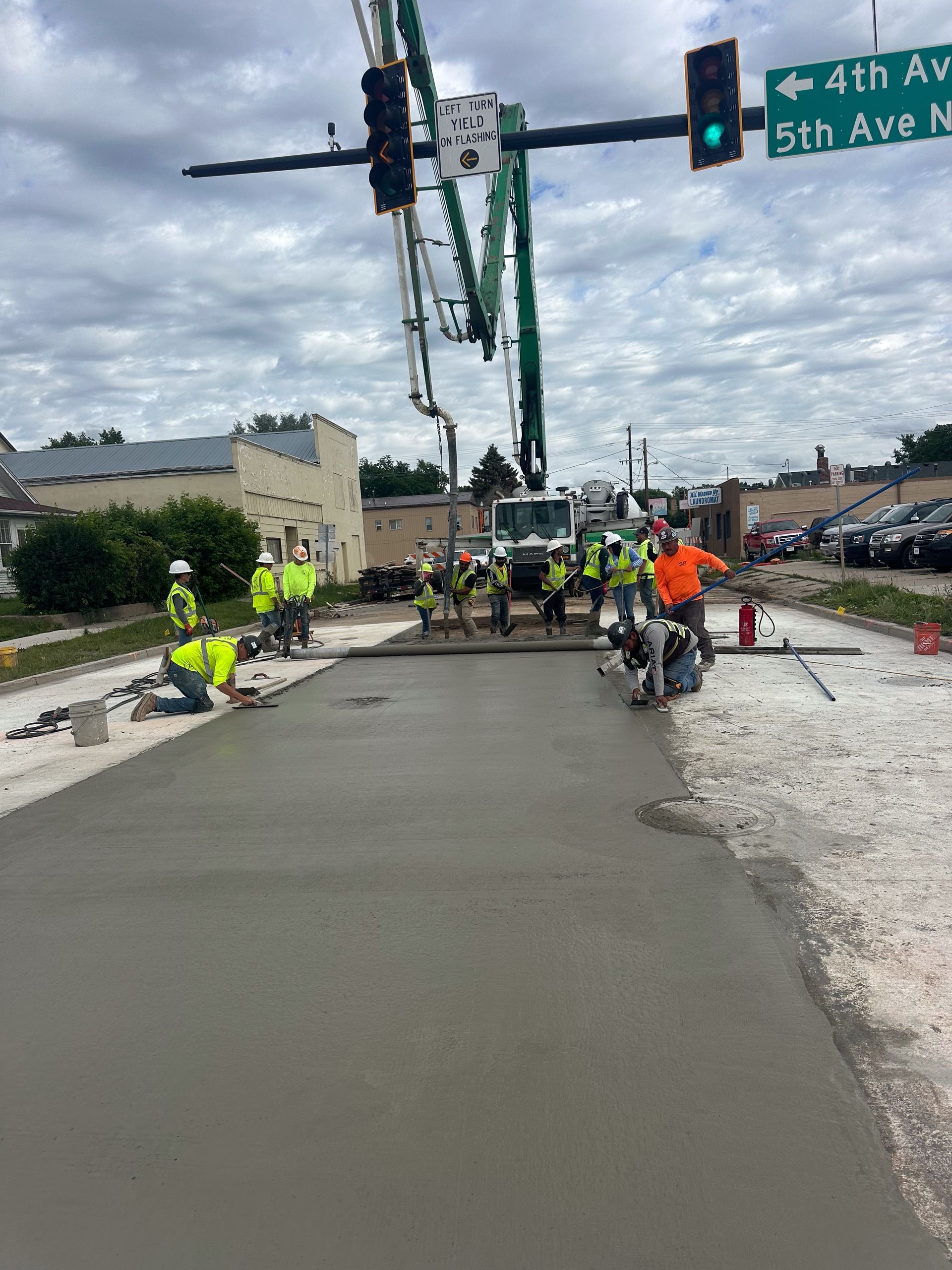 A group of construction workers are laying concrete on a street.