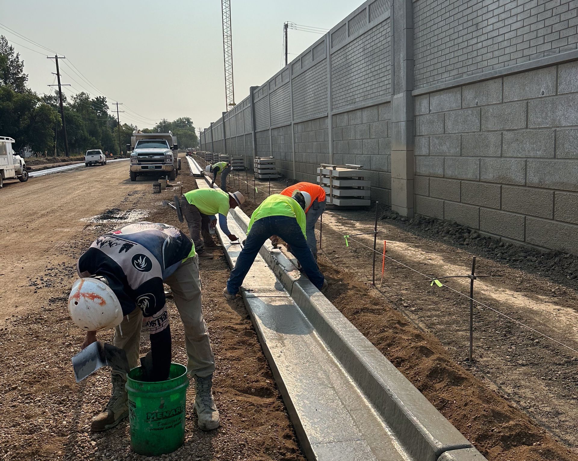 A man is laying concrete on a sidewalk with a trowel.
