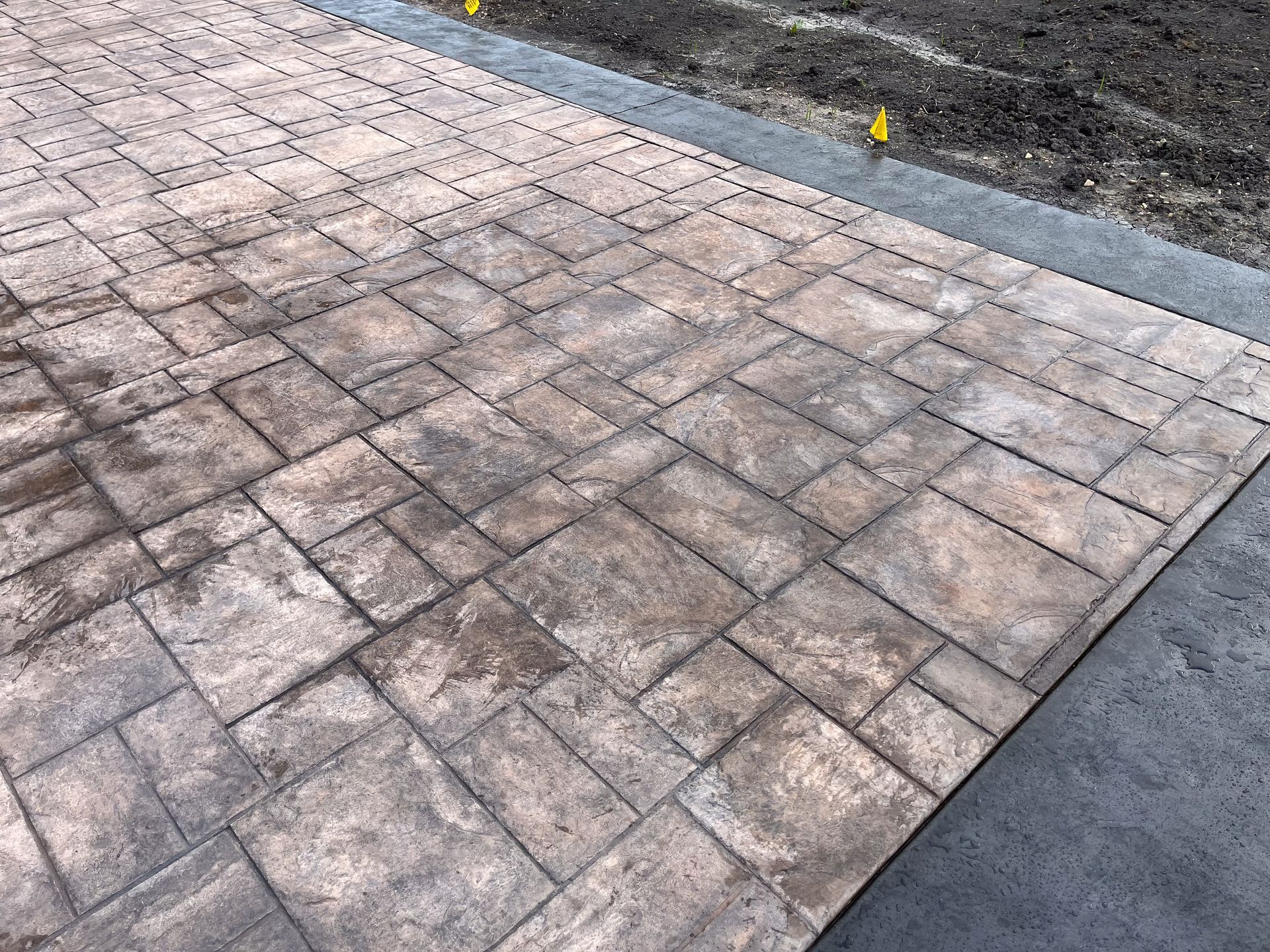 A close up of a brick driveway with a concrete curb.