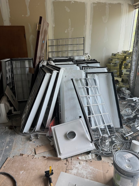Construction debris: shower bases, doors, and metal racks in a room under construction.