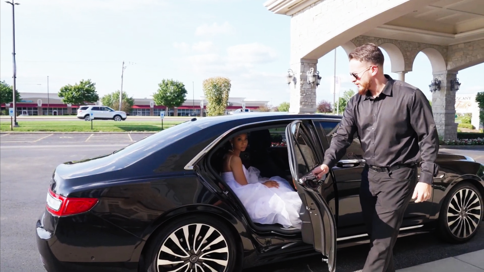 Chauffeur from M.R. Black Car Service opening the door for a bride at Tuscany Falls Banquet in Mokena, Illinois, with a black Lincoln Continental.