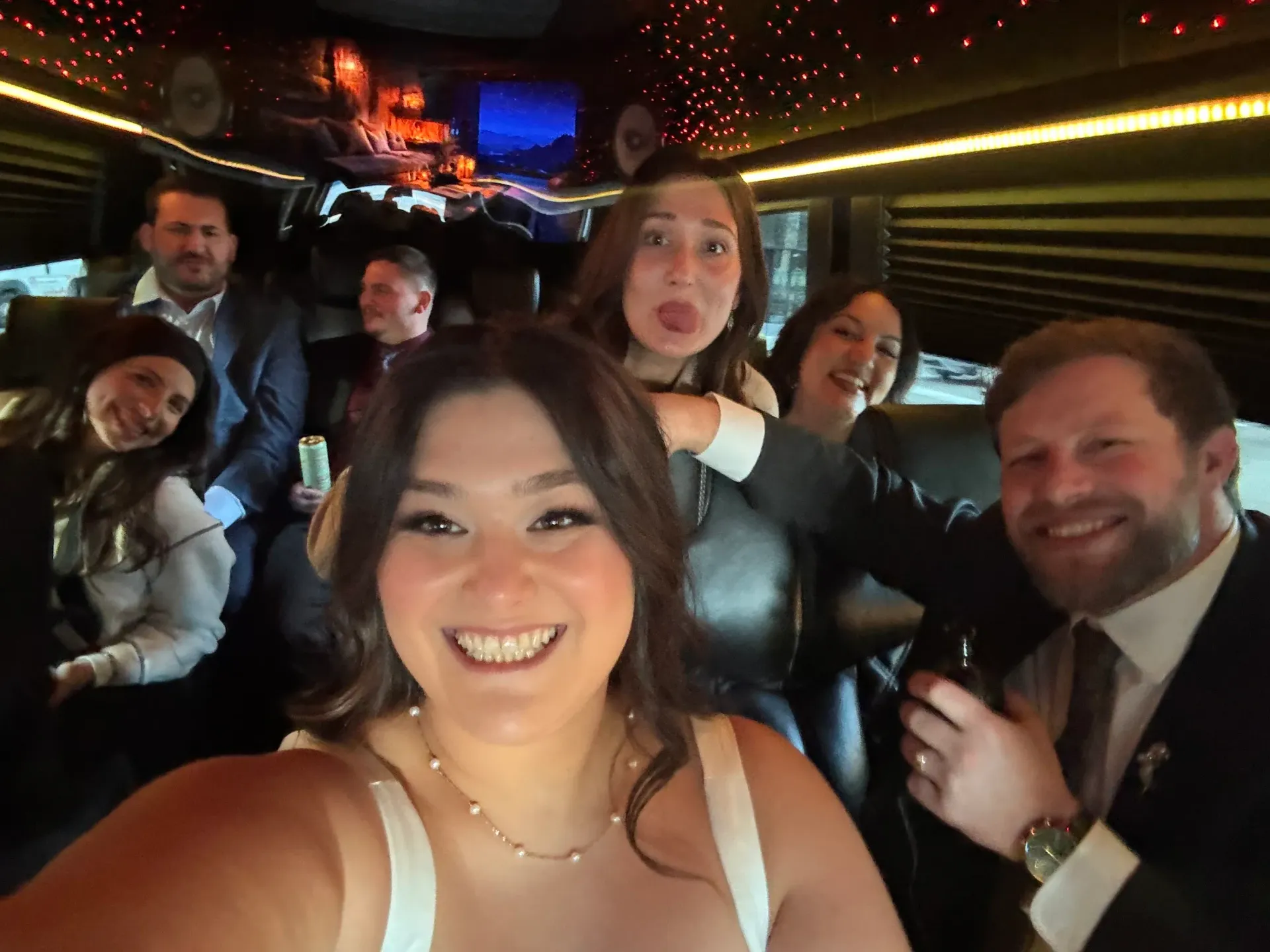 Wedding party celebrating inside a stretch limo with ambient lighting — group transportation by M.R. Black Car Service.