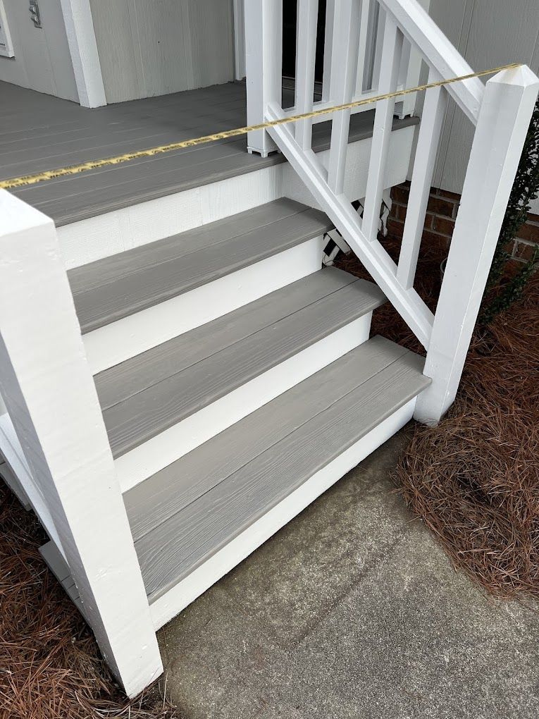 A set of stairs leading up to a porch with a white railing.