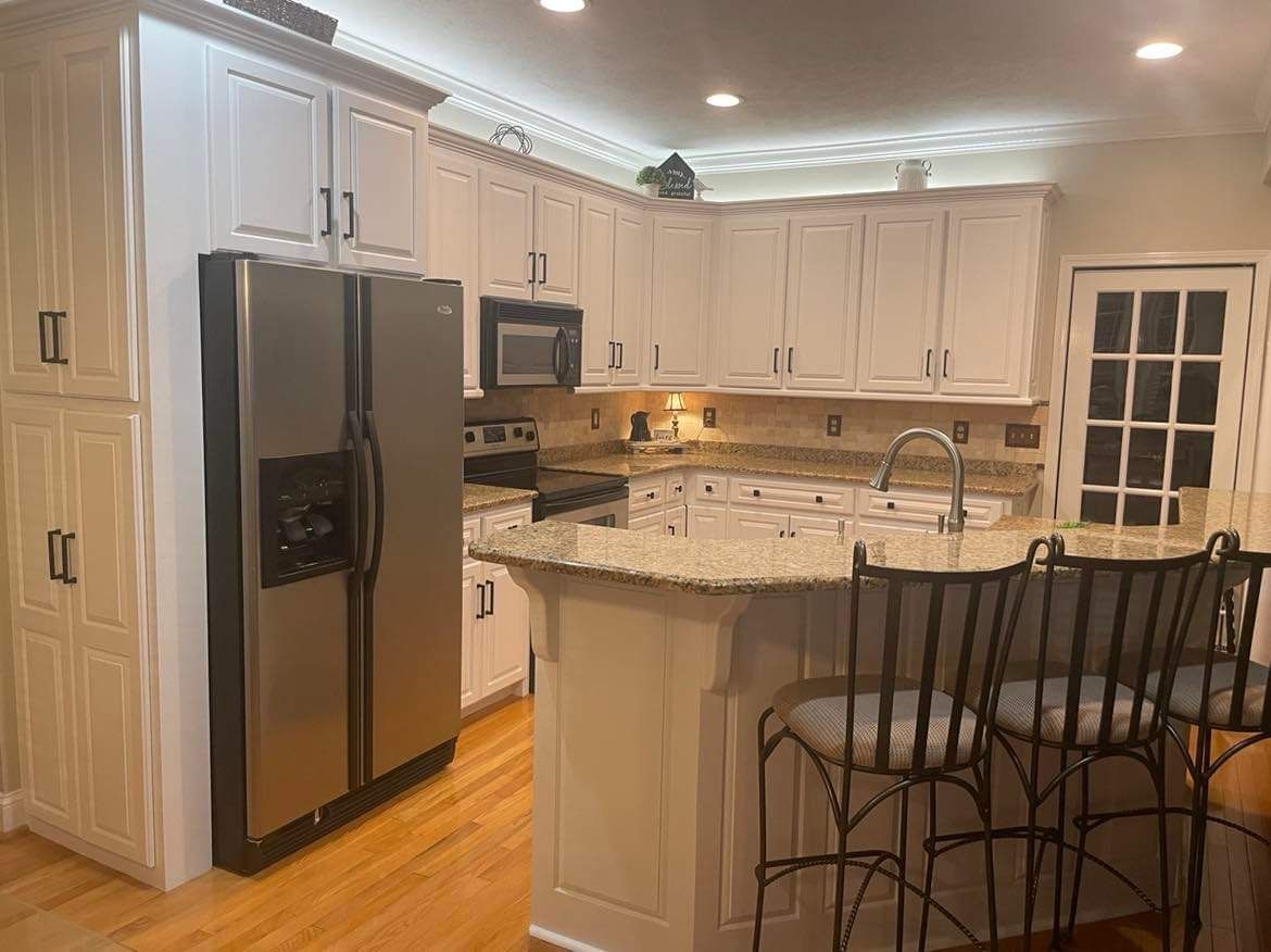 A kitchen with white cabinets , stainless steel appliances , granite counter tops , and a large island.