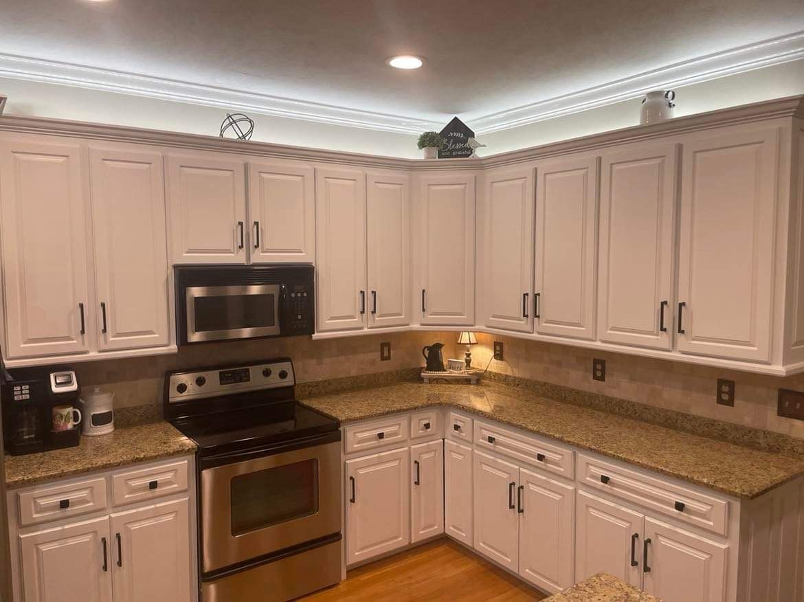 A kitchen with white cabinets , stainless steel appliances , granite counter tops and a stove.