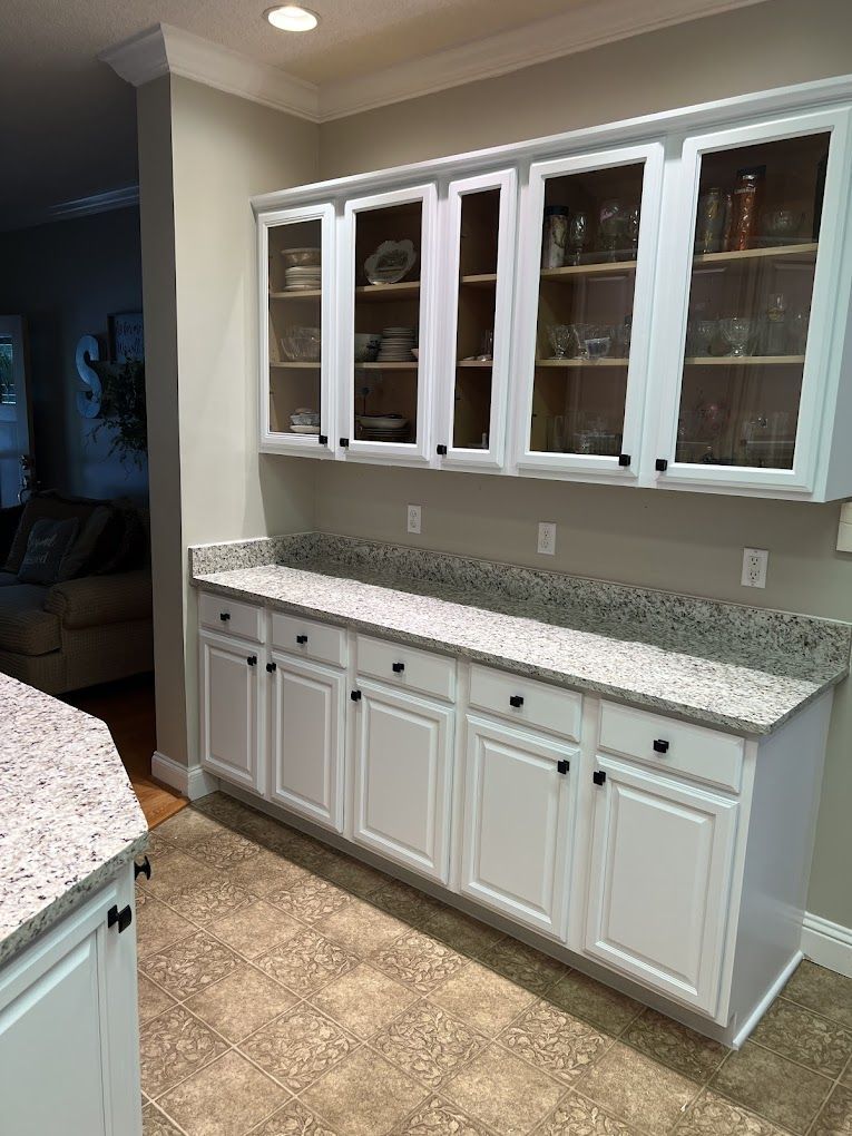A kitchen with white cabinets and granite counter tops.