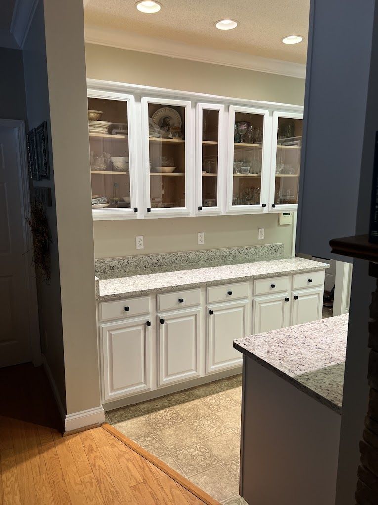 A kitchen with white cabinets and granite counter tops.
