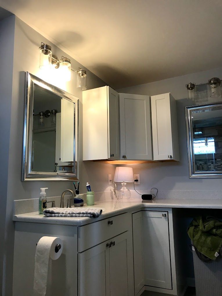 A bathroom with a sink , mirror and cabinets.