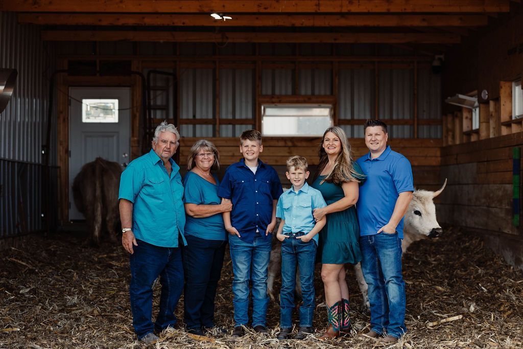 A family standing next to a herd of cows in a field.