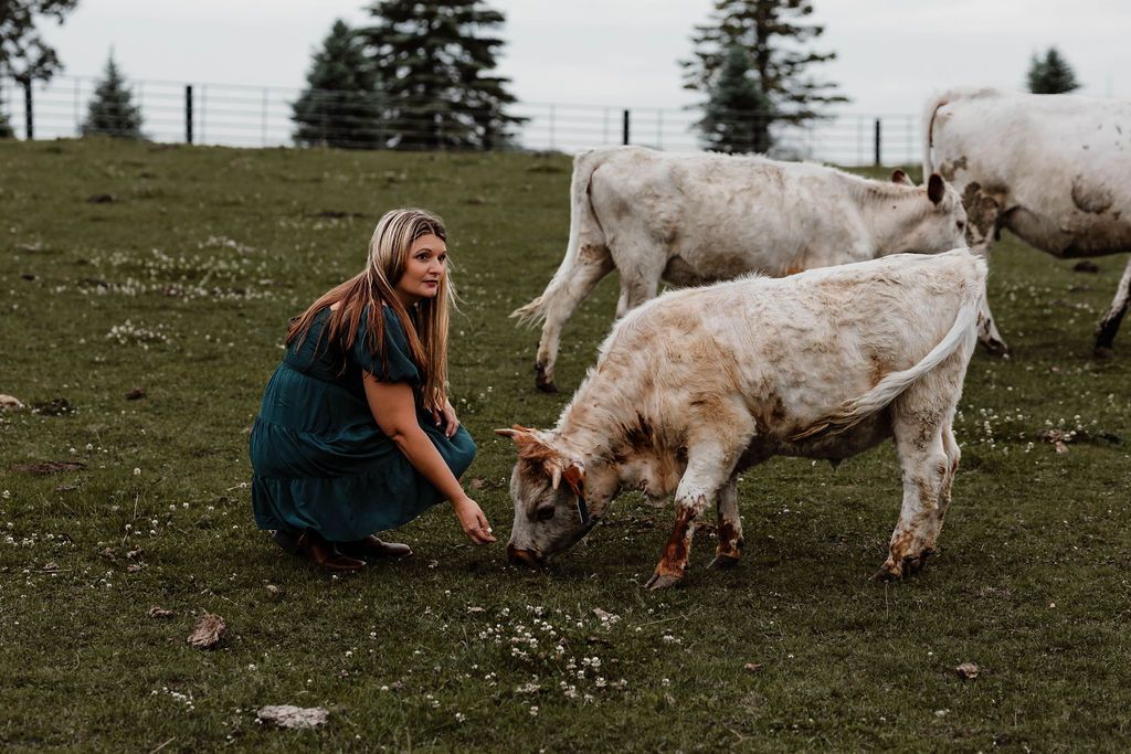 Jamie is kissing a brown cow in a field.