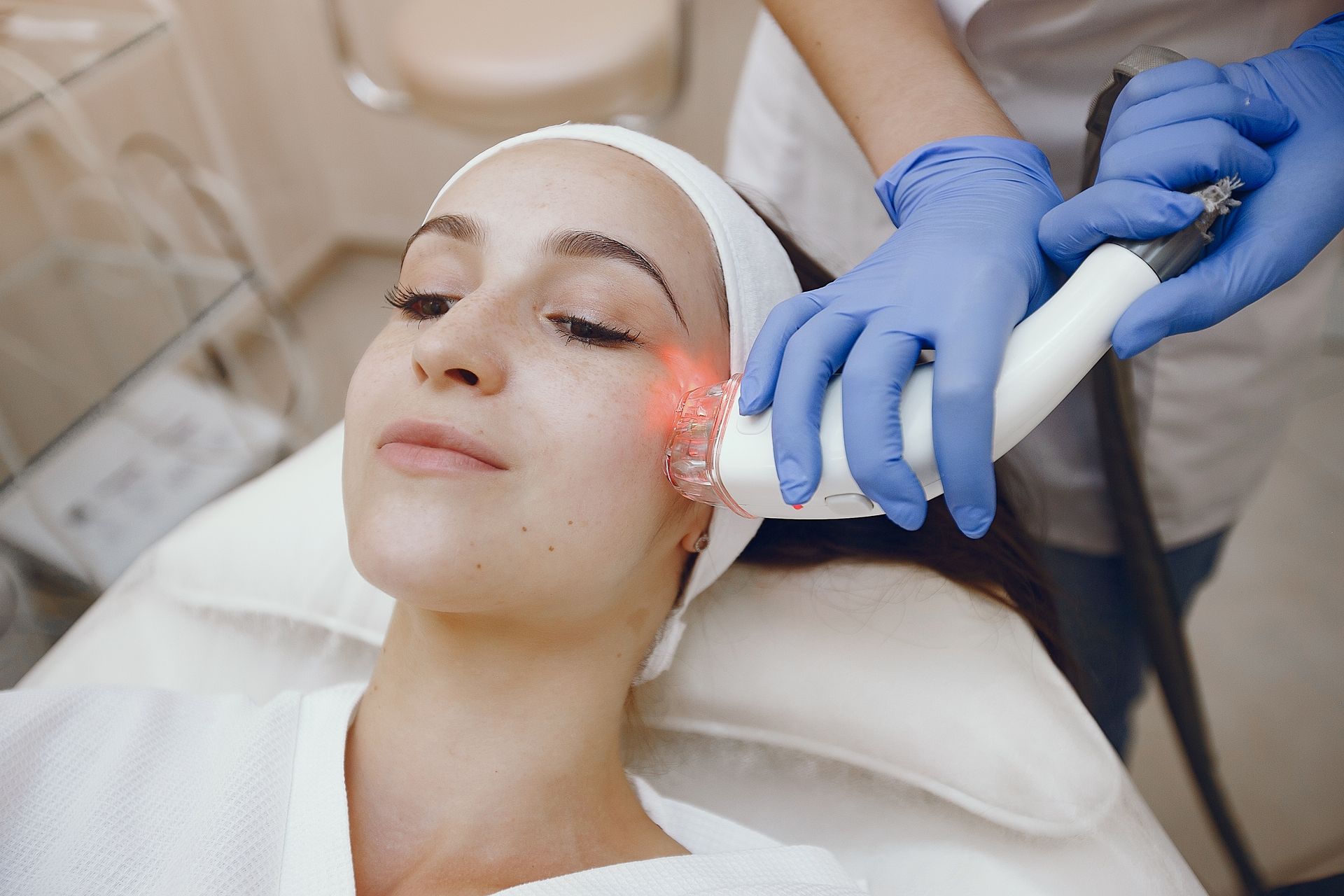 A woman is getting a laser treatment on her face in a beauty salon.