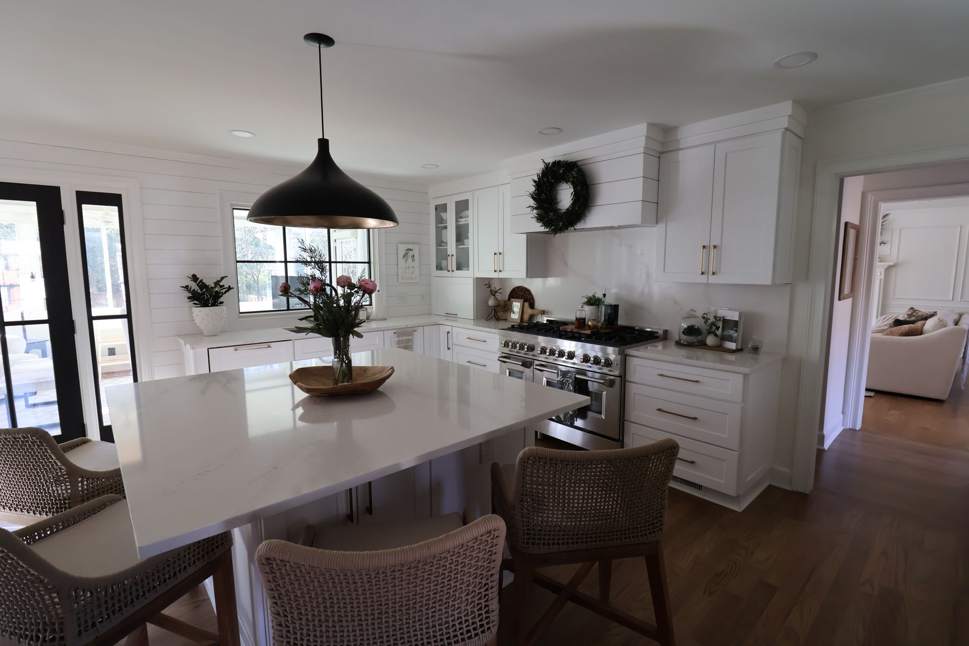 A kitchen with white cabinets , a stove , a table and chairs.