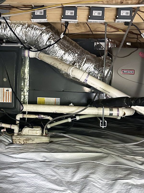 A picture of a basement with a lot of pipes and wires.