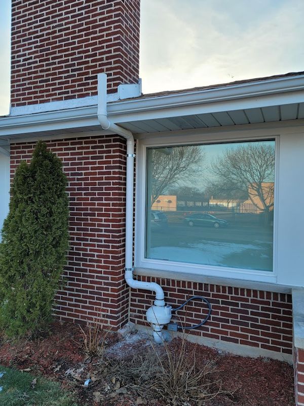 A brick house with a white window and a white gutter.
