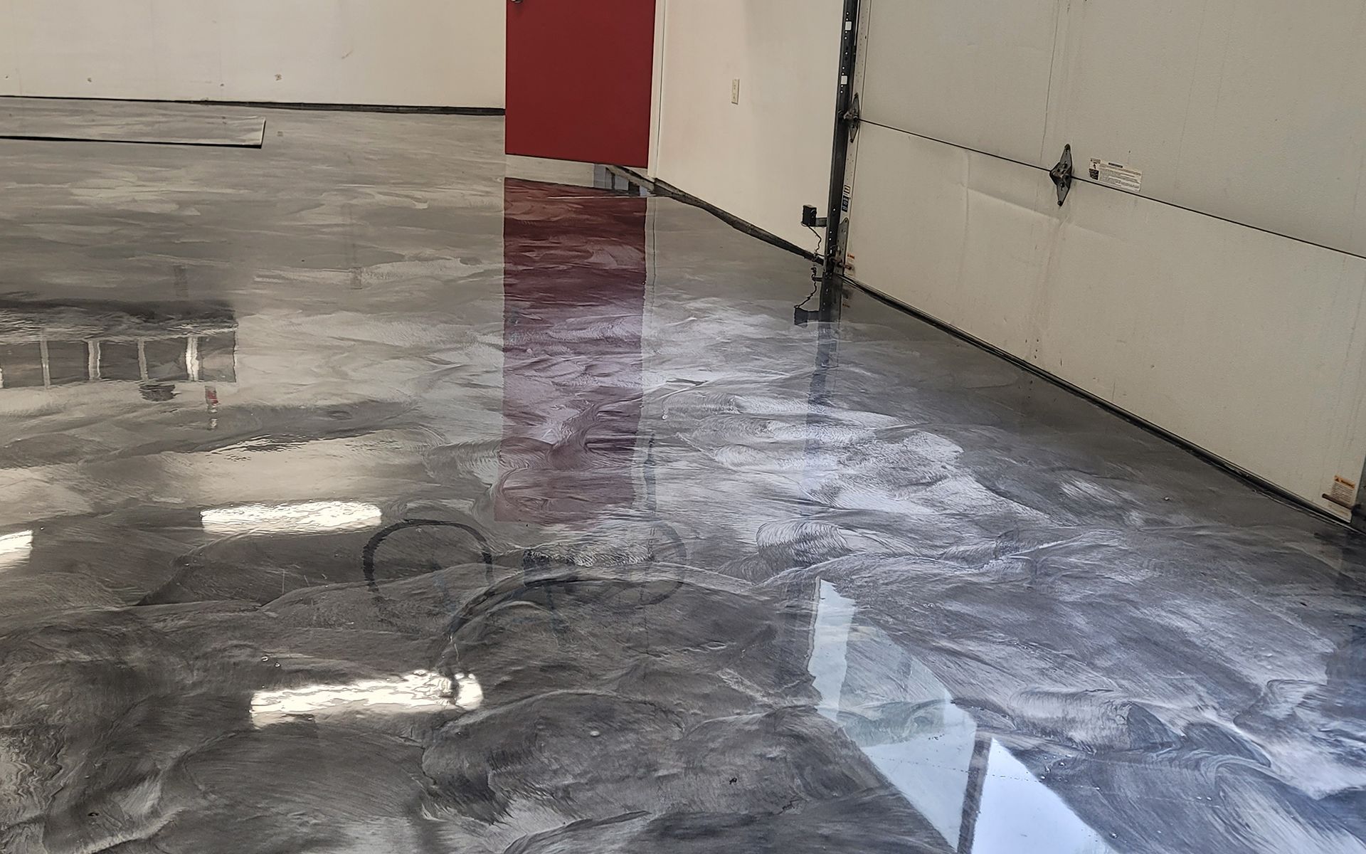 A garage with a shiny metallic floor and a garage door.