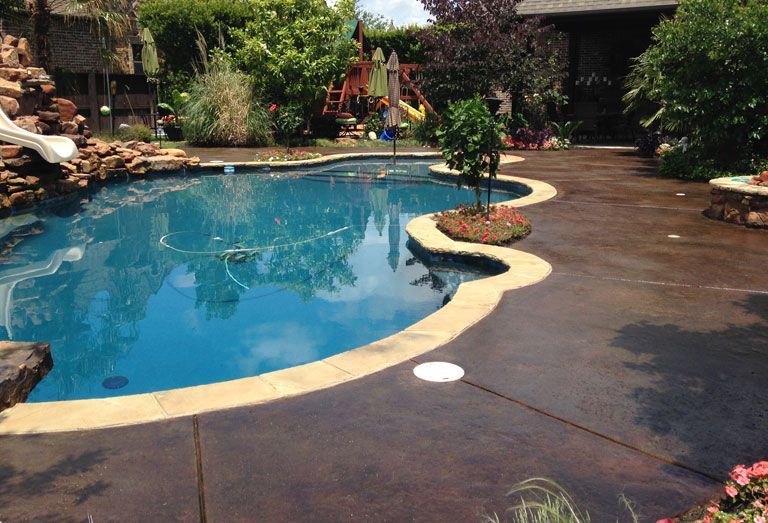 A large swimming pool is surrounded by a concrete deck.