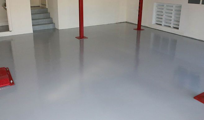 A garage with a gray floor and red poles.
