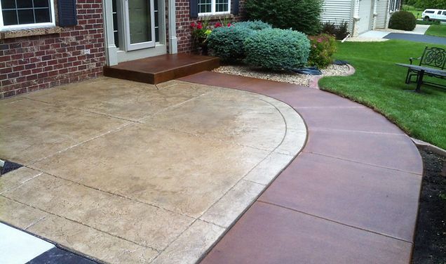 A brick house with a concrete walkway leading to it.