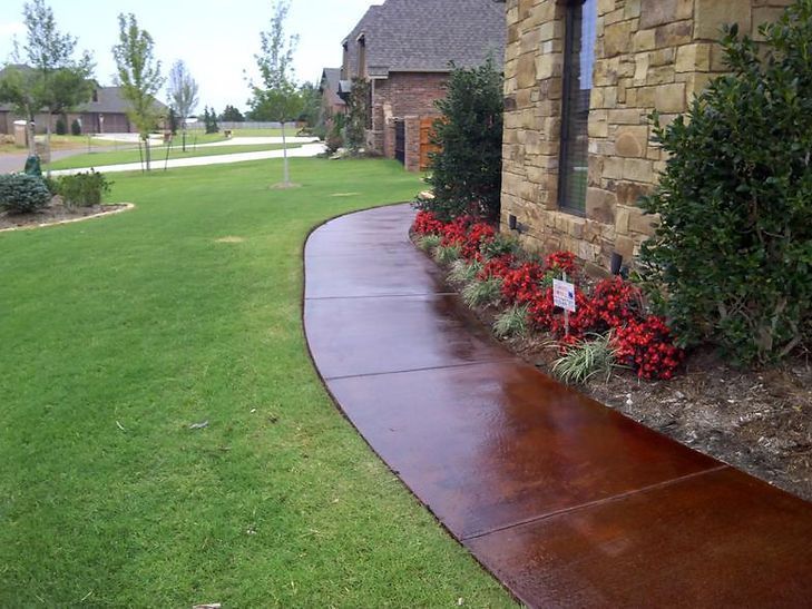 A walkway leading to a house with flowers on the side