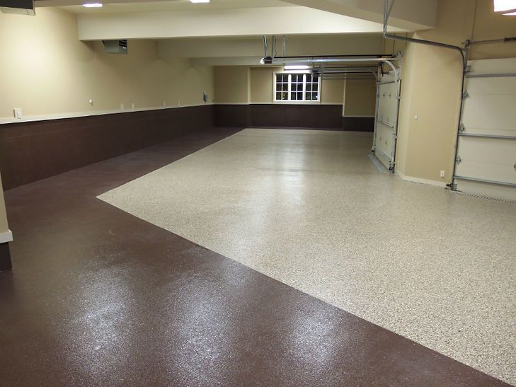 A garage with a brown and white floor and a garage door.