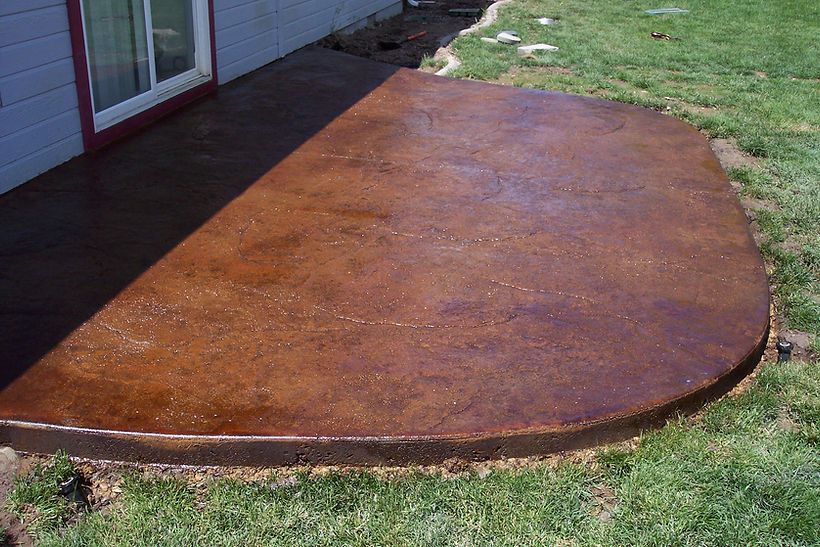 A concrete patio is sitting in the grass in front of a house.
