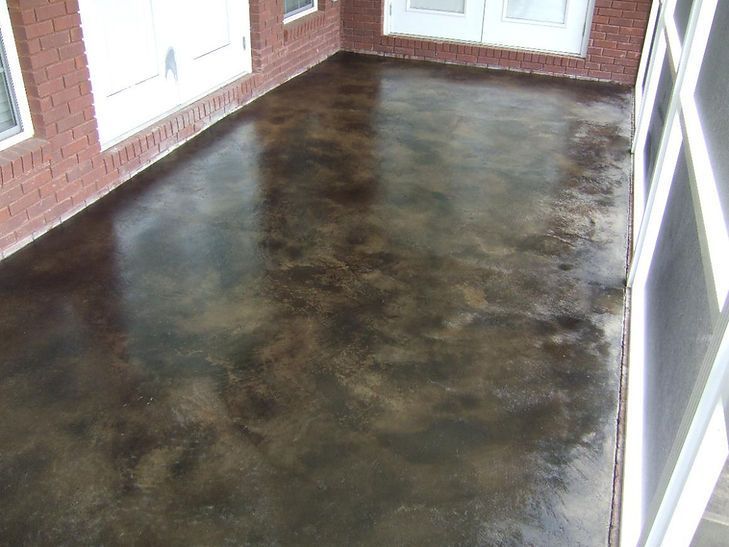 A porch with a brick wall and a concrete floor
