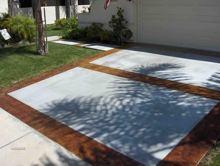 A concrete driveway with a palm tree shadow on it