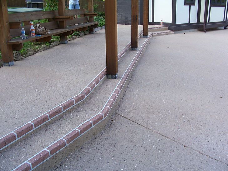 A concrete walkway with a wooden fence in the background