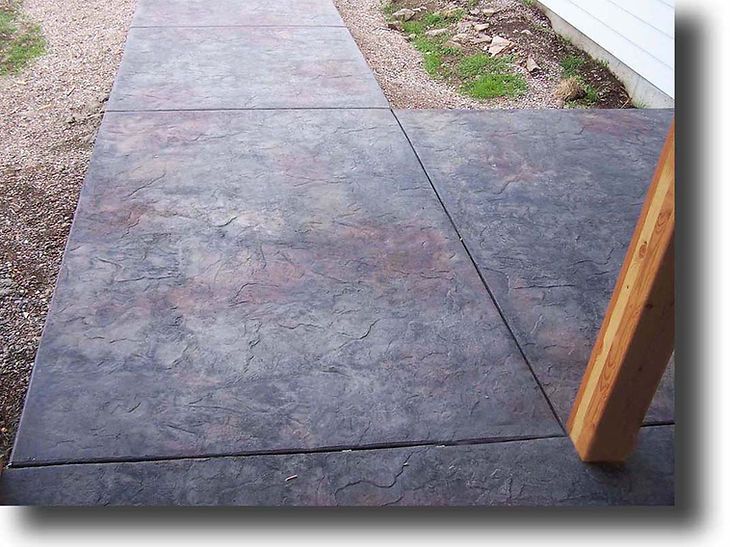 A concrete walkway with a wooden post in the foreground