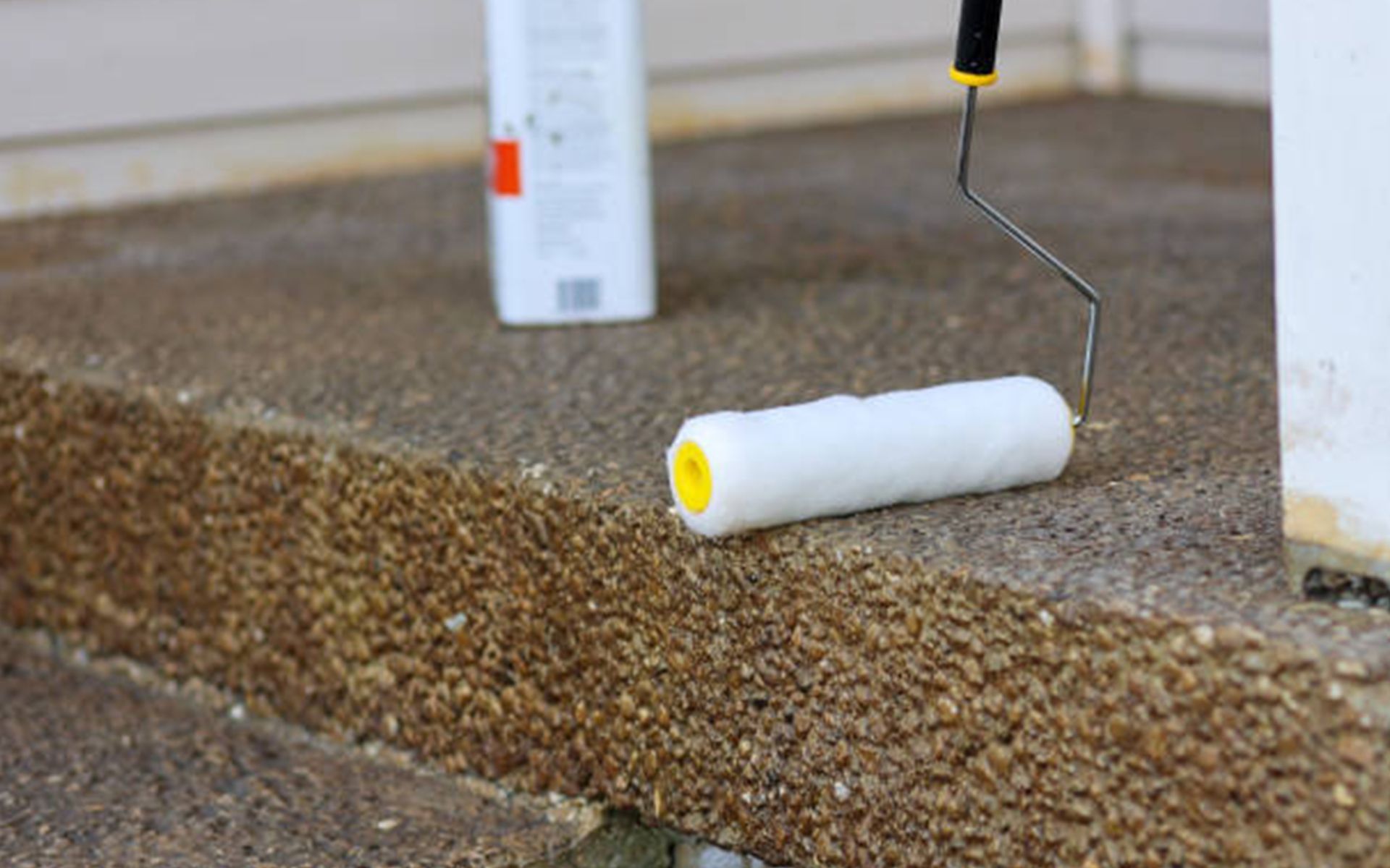 A roller is being used to paint a concrete floor.