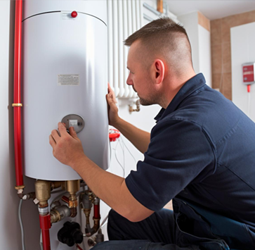Plumber adjusting water heater controls. Indoors, against white wall. Red pipes, brass fittings visible.
