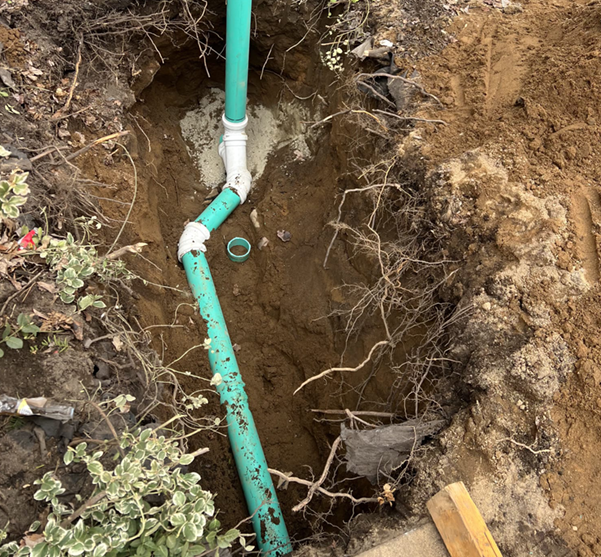 Person using wrench to tighten plumbing pipe under a sink.