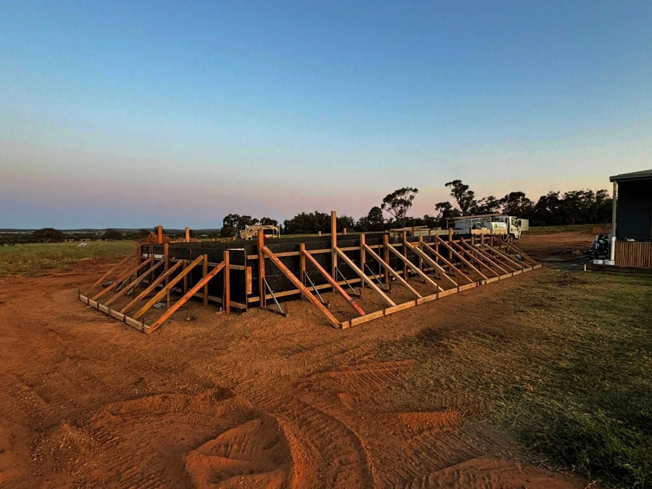 A Large Wooden Structure is Sitting in the Middle of a Dirt Field — Spencer's Landscape Construction & Concreting Pty Ltd in Orange, NSW