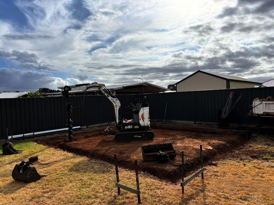 A Small Excavator is Sitting in the Dirt in a Backyard — Spencer's Landscape Construction & Concreting Pty Ltd in Coonamble, NSW