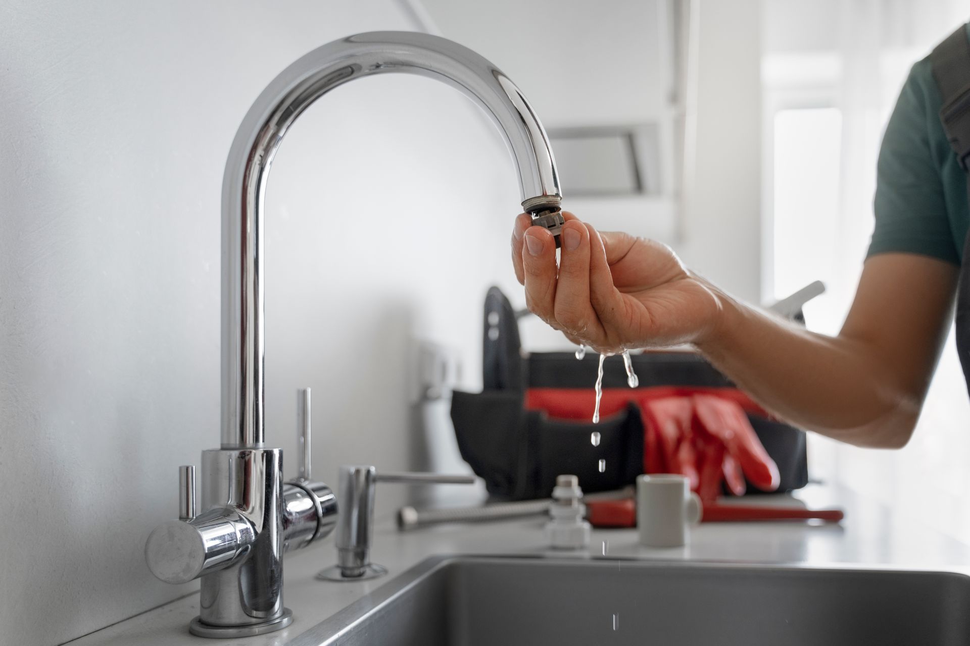 A person is fixing a faucet in a kitchen.