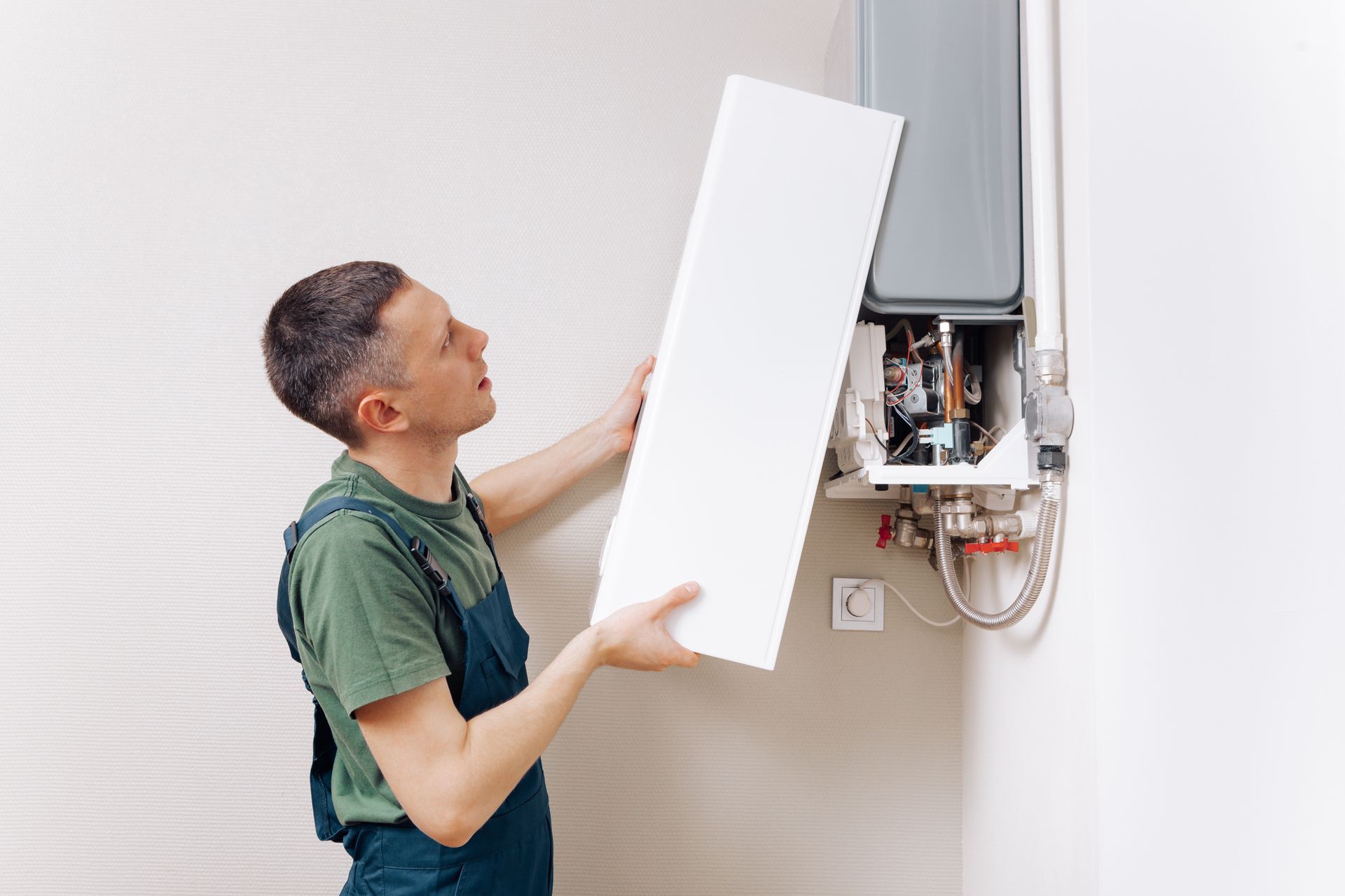 A man is holding a piece of paper in front of a water heater.