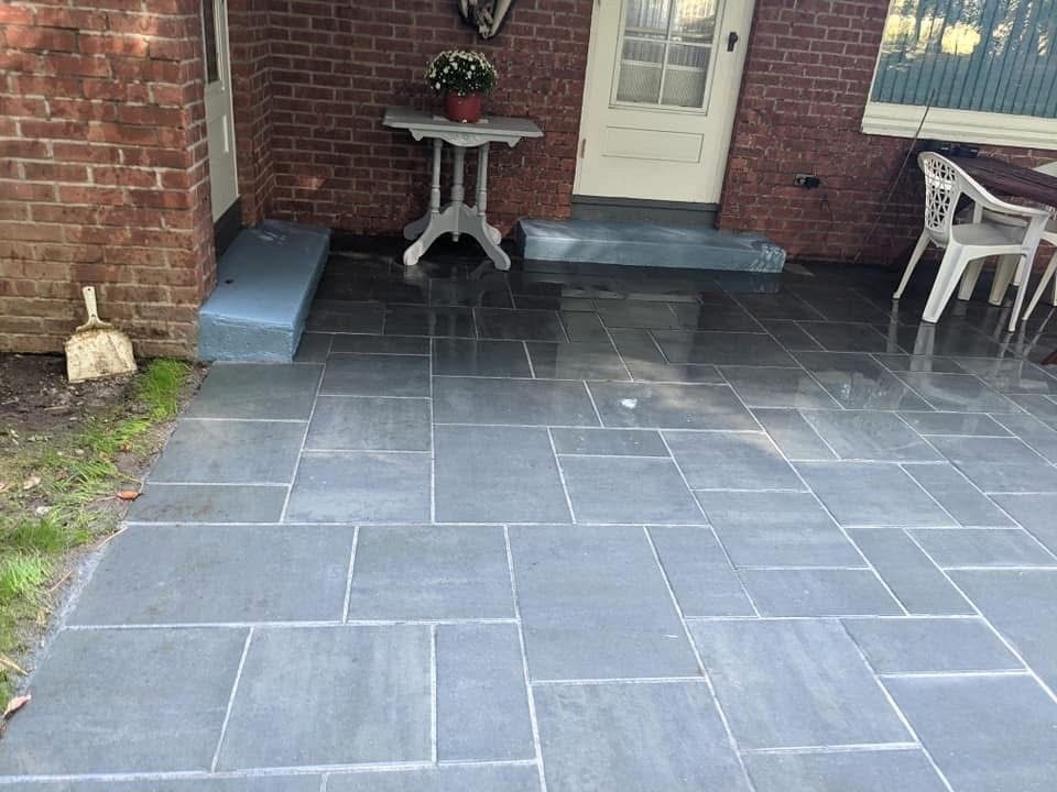 Person laying pavers in a backyard with a playground, creating a circular patio with a surrounding wall.