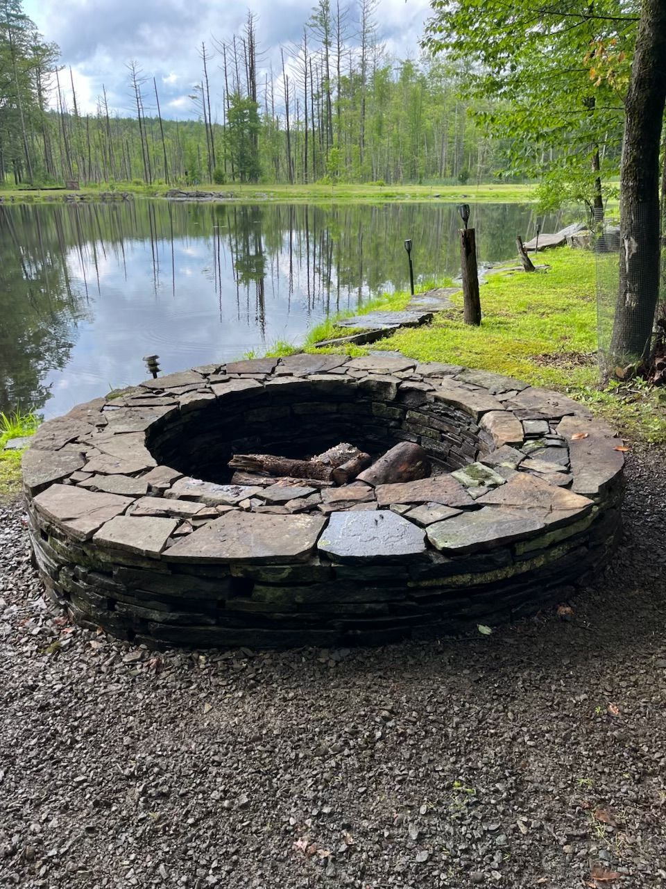 Outdoor patio with a round dining table set for guests, grill, and stone features.