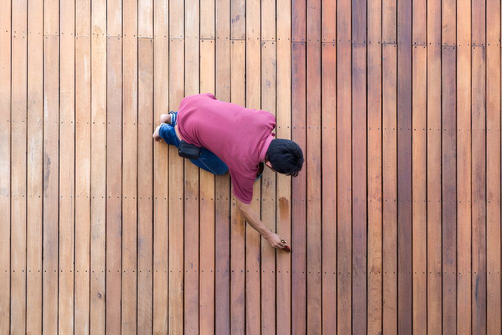 A Man Is Restoring Wooden Floor — European Floor Sanding In Mount Louisa, QLD